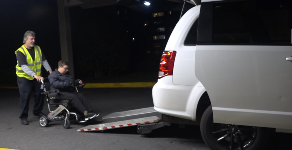 Wheelchair user Kelly Mack being helped into a wheelchair accessible Uber via a back door ramp